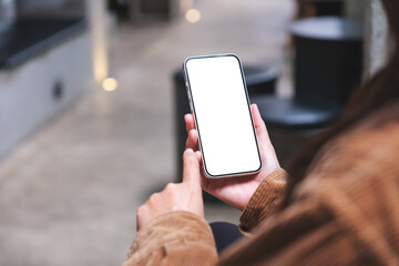 Mockup image of a woman holding and using mobile phone with blank desktop screen
