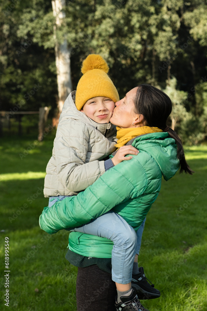 Mother kissing son in yellow hat. Lifestyle portrait. Connection between mother and child.
