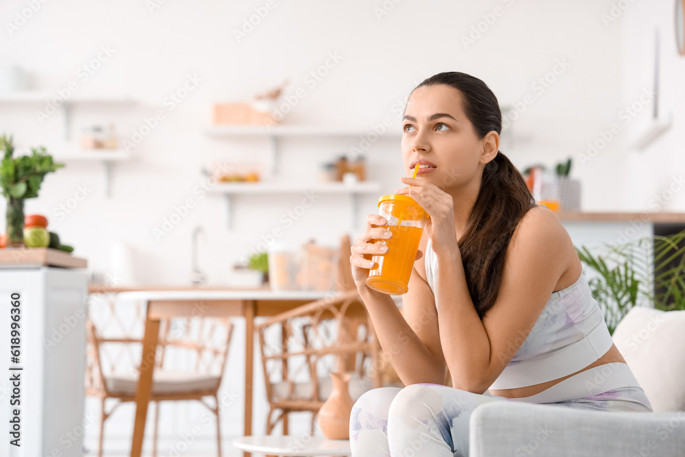 Sporty young woman drinking vegetable juice in kitchen Stock Photo