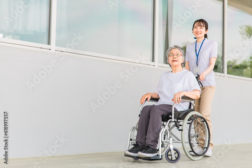 病院・介護施設で散歩する車椅子に乗った高齢者と介護士（ヘルパー・理学療法士・コピースペース） 