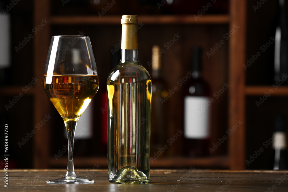 Bottle and glass of exquisite wine on table in cellar
