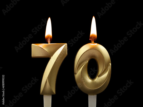 Burning gold birthday candles isolated on black background. Number 70. photo