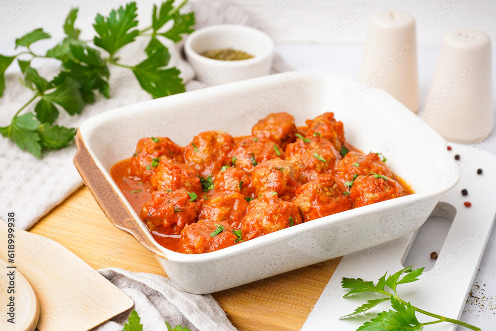 Baking dish of tasty meat balls with tomato sauce and parsley on white background Baking dish of tasty meat balls with tomato sauce and parsley on white background