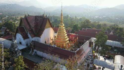 Aerial drone view of beautiful golden pagoda at Wat Phra That Cho Hae Temple in Phrae province, Thailand. Ancient temple in the middle the jungle, Travel destination photo