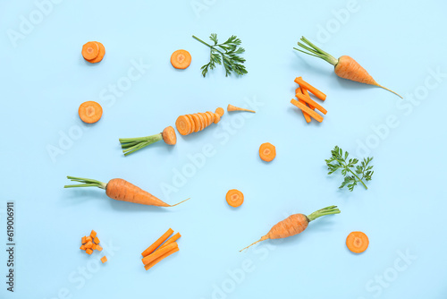 Fresh carrots and slices on blue background