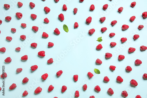 Frame made of fresh raspberries and mint on blue background