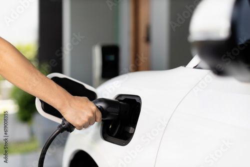 Progressive concept of hand insert an emission-free power connector to the battery of electric vehicle at home. Electric vehicle charging via cable from charging station to EV car battery
