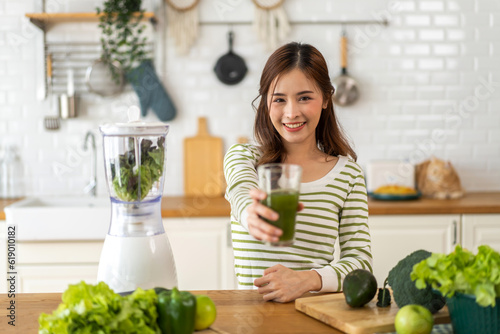 Portrait of beauty healthy asian woman making green vegetables detox cleanse and green fruit smoothie with blender.young girl drinking glass of smoothie  fiber  chlorophyll in kitchen.Diet  healthy