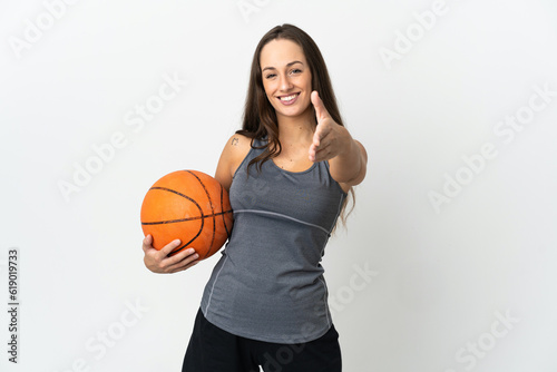 Young woman playing basketball over isolated white background shaking hands for closing a good deal