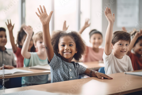 Happy little student raising her hand. School children in classroom at lesson