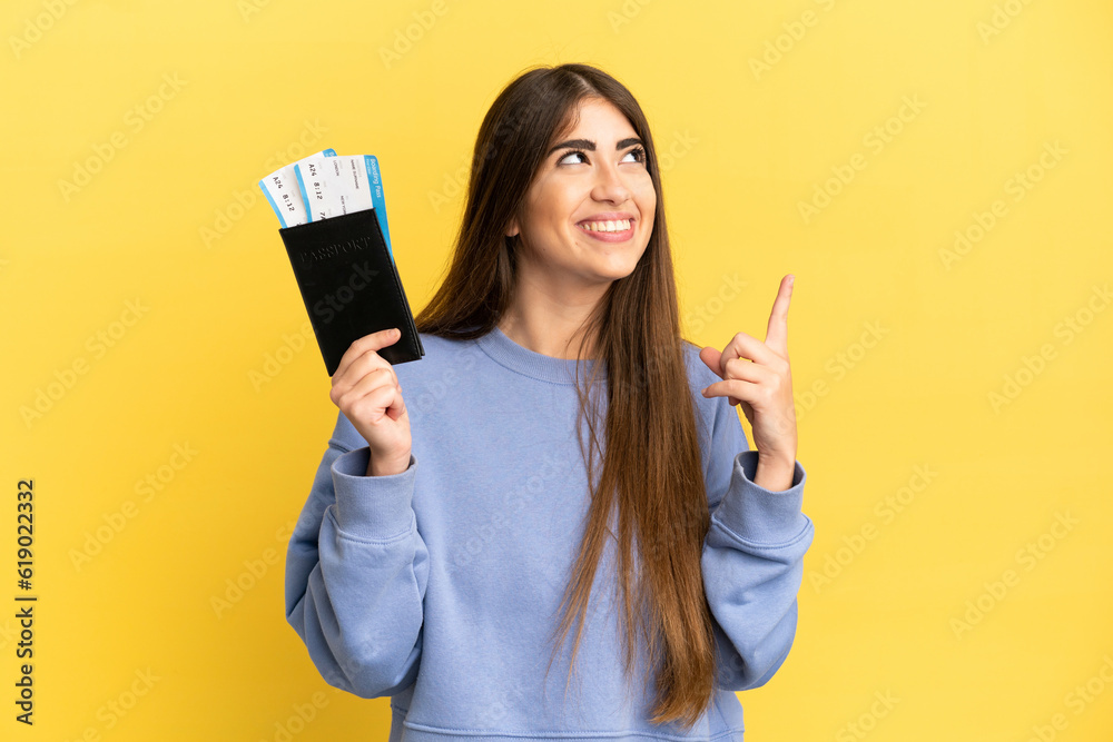 Young caucasian woman holding a passport isolated on yellow background pointing up a great idea Young caucasian woman holding a passport isolated on yellow background pointing up a great idea