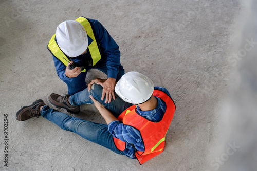 top view of construction workers had an accident suffering misfortune physical  knee injury from working at site, senior men helping young colleague after dangerous accident, safety and risk concept