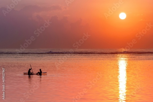 View of a couple leisurely enjoying a paddleboat ride on the beach at sunset