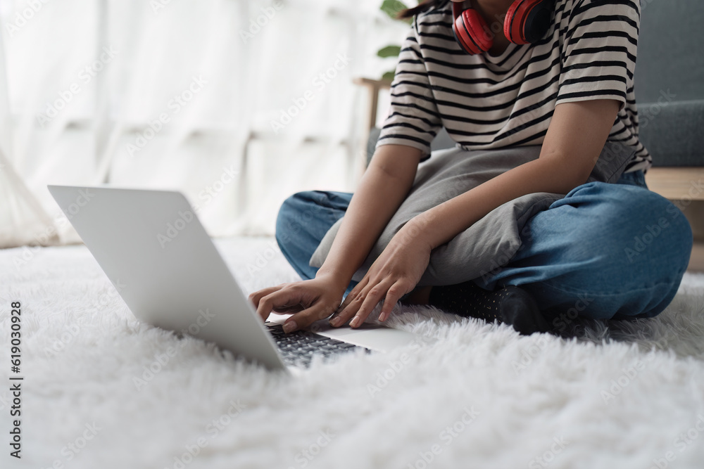 Naklejka premium Young asian relaxed smiling pretty woman relaxing with laptop at home. Female feeling joy enjoying with mobile phone on cozy couch