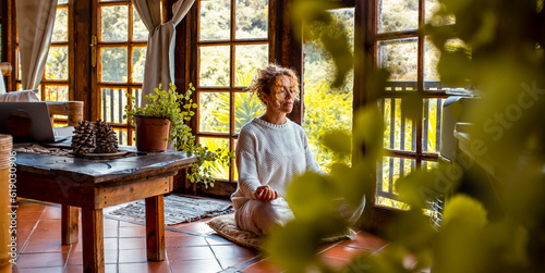 Interior balance and love for yourself concept lifestyle. One middle age youthful woman doing meditation in yoga asana position at home sitting on the floor. Healthy natural exercise. Mental wellbeing