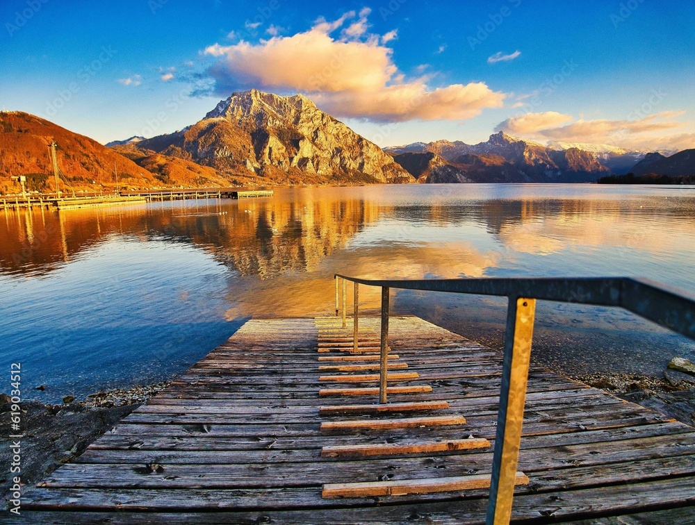 Obraz premium Scenic view of a wooden platform over the calm Traunsee lake against mountain landscape in Austria