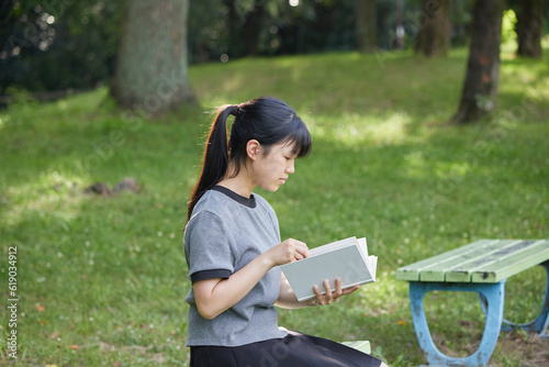 夏の公園で読書している中学生の子供の様子