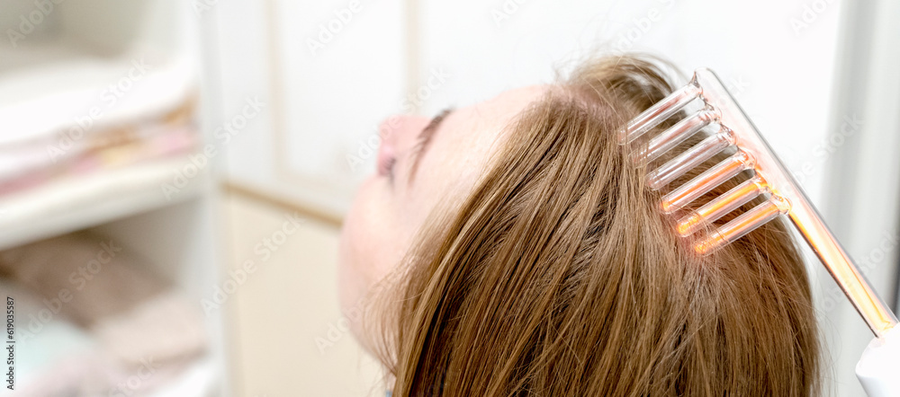 Fototapeta premium the girl does the procedure of darsonvalization of the hair of the head
