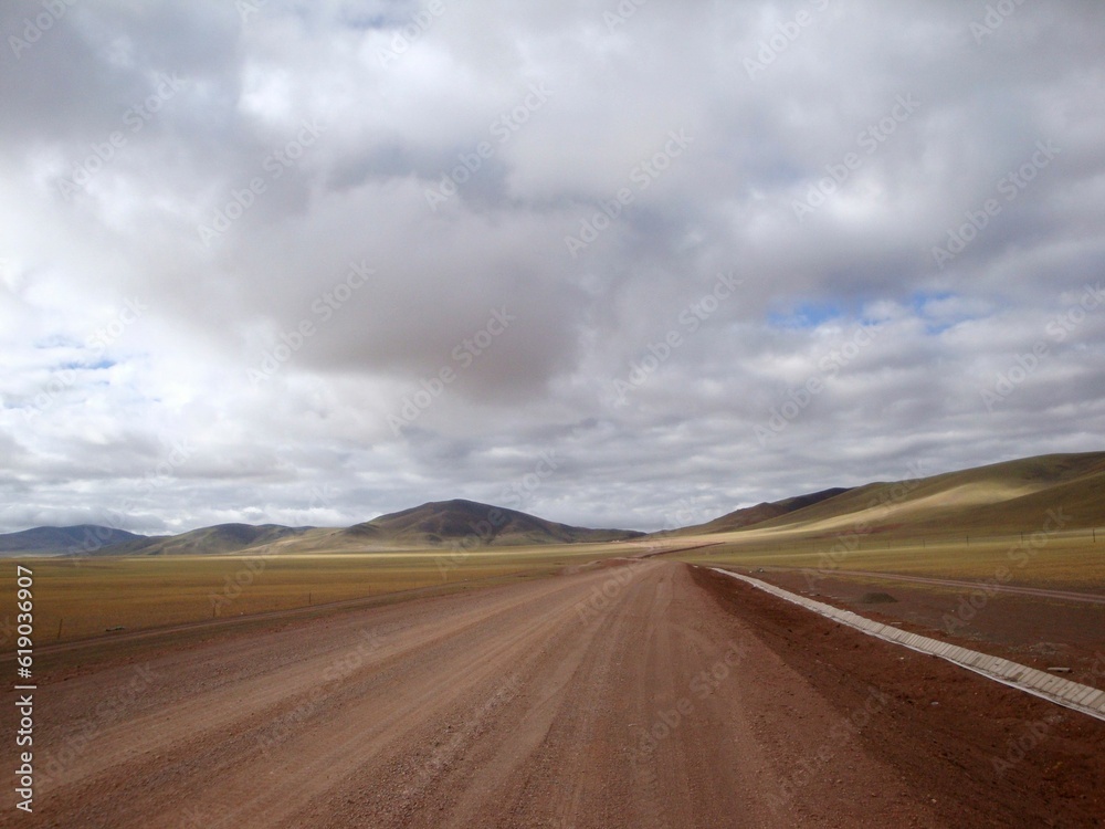 Beautiful view of a gravel road against mountains and cloudy sky