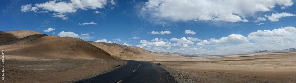 Panoramic shot of an empty road against mountains and a cloudy sky