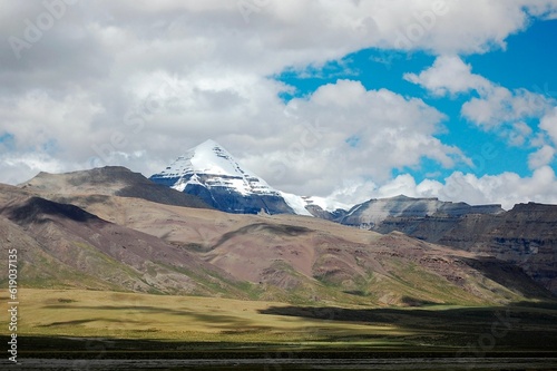 Low-angle of snowy Kangrinboqe peak with a yellow steppe view  cloudy sky background