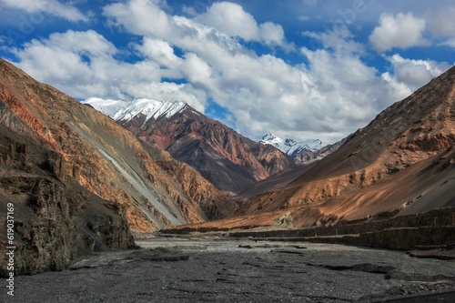 Beautiful landscape with big mountains with snowy peaks against the blue cloudy sky