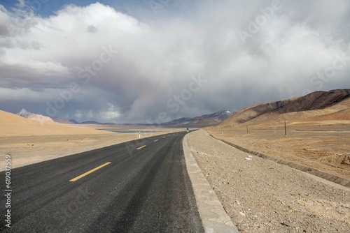 Aerial view of road through desert surrounded by hills © Hazel Ma1/Wirestock Creators