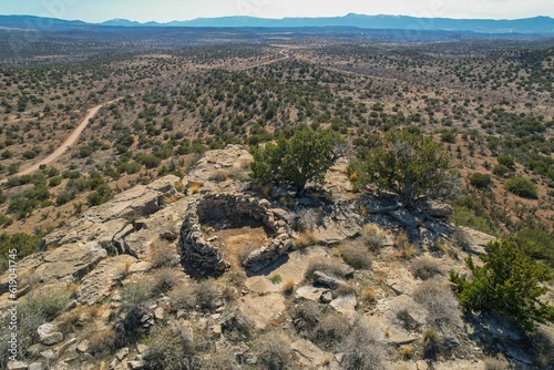 Scene of a Sinagua pueblo situated atop a plateau with trails winding through the landscape