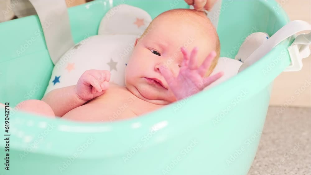 A newborn baby takes a bath. A lovely child is undergoing military