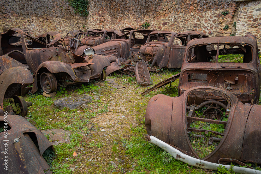 Abandoned scrapyard with old rusty cars in the destroyed village of Oradour sur Glane in France