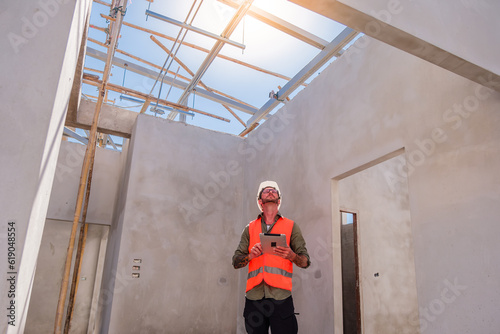 White man construction worker inspecting the building work with tablet.