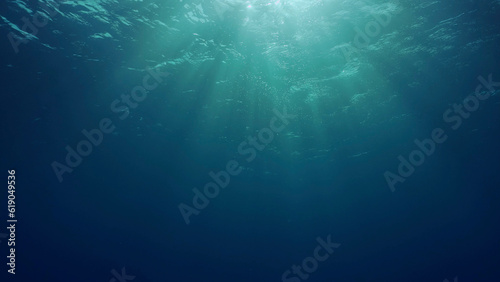View of sun light from blue abyss, slow motion. Light filters down through blue water. Underwater sun rays in depth ocean. Underwater sun light shine under deep water with ripples on waves surface © Andriy Nekrasov