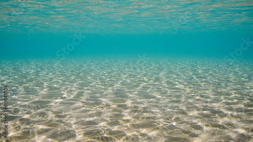 Sandy shallow water in sunburst and glare on seabed sand. Sunlight passes through surface of turquoise water and glares on sandy bottom in shallow water on bright sunny day, Red sea, Egypt