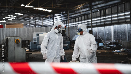 Scientist workers wear protection suit checking chemical contaminated oil in old factory. Red and White Lines Marking a Dangerous Zone. Biohazard Contamination Control.
