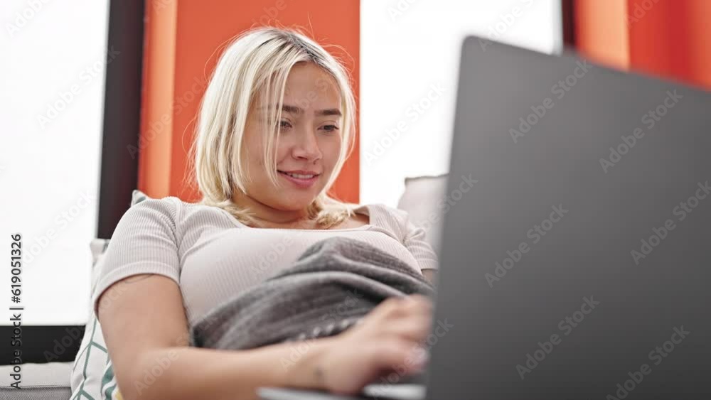 Young beautiful hispanic woman using laptop lying on sofa at home Young beautiful hispanic woman using laptop lying on sofa at home
