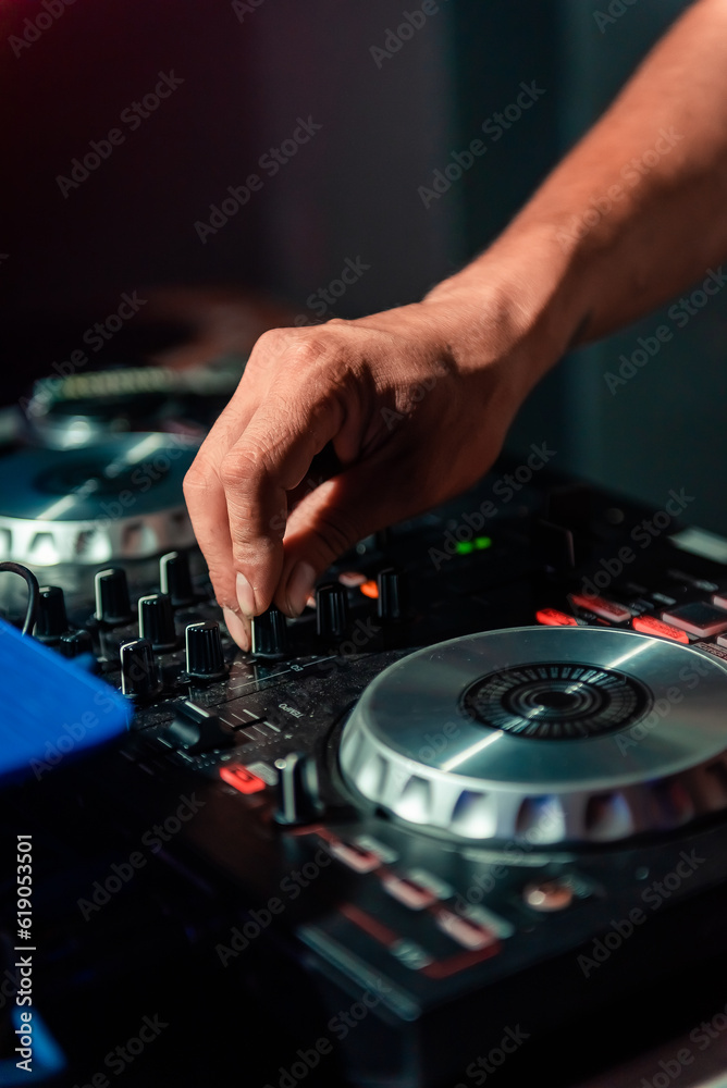 Obraz premium A cool DJ standing at the mixer controller, composing a new mix and making the party in a nightclub nightlife concept. dj concept. party concept