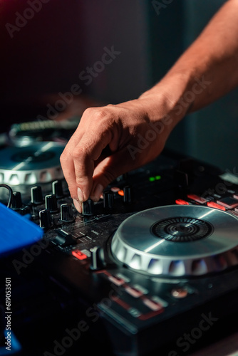 A cool DJ standing at the mixer controller, composing a new mix and making the party in a nightclub nightlife concept. dj concept. party concept