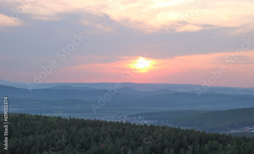 Sunset over mountains and countryside village, sky in soft pastel colors.