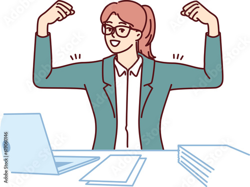 Businesswoman showing biceps on hands sitting at office table with laptop and demonstrating ambition