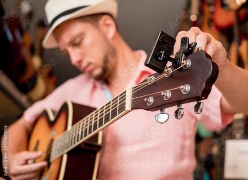 Young musician tuning a classical guitar in a guitar shop