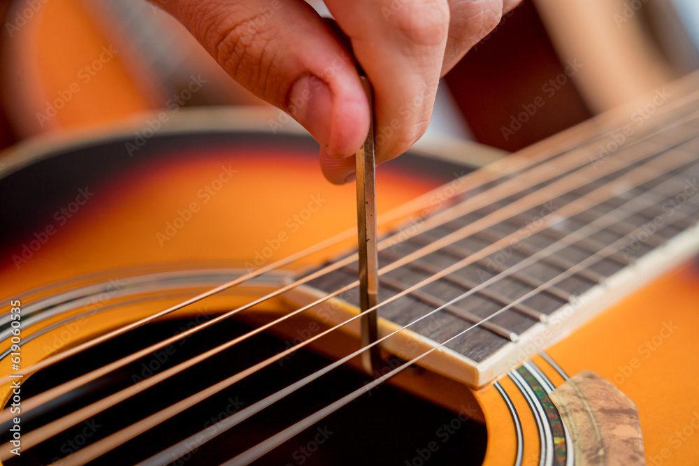 Fototapeta premium Young musician tuning a classical guitar in a guitar shop