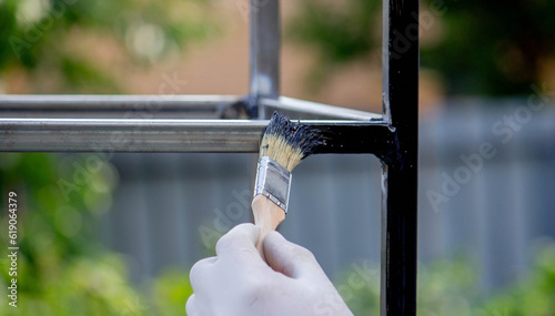 a man paints metal with black paint with a brush.