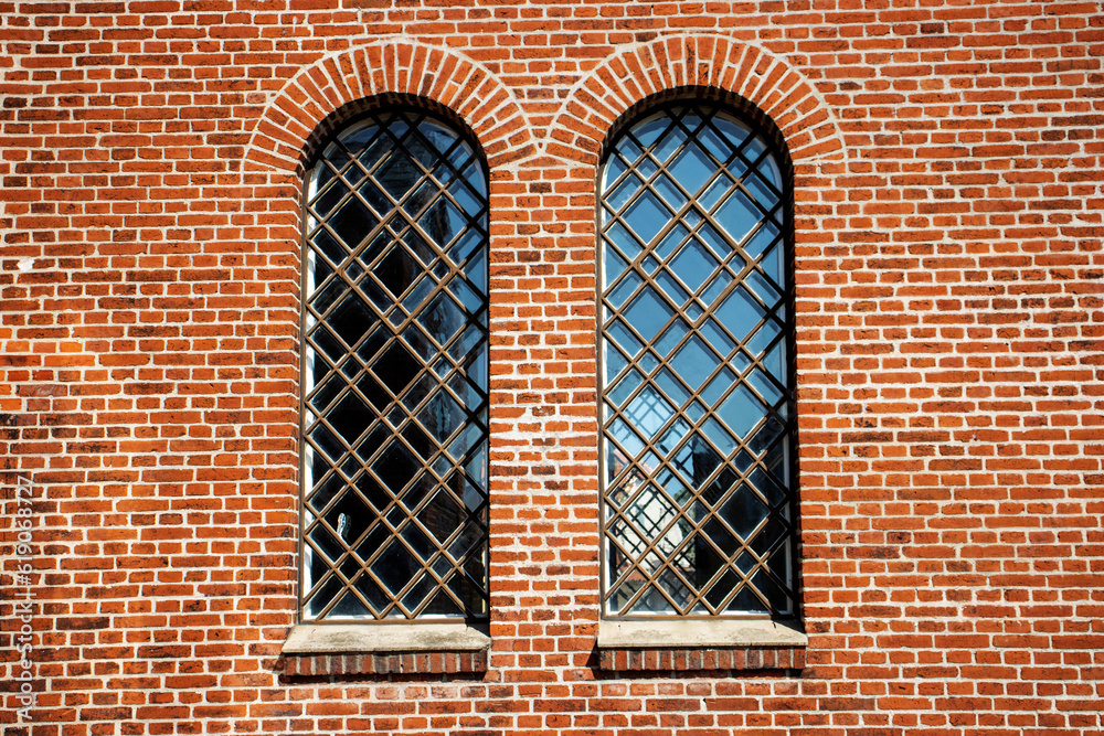 two tall narrow windows in a red brick wall with bars