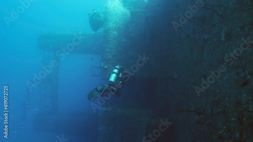 Scuba diver swim along deck of ferry Salem Express shipwreck, Back view, Red sea, Safaga, Egypt