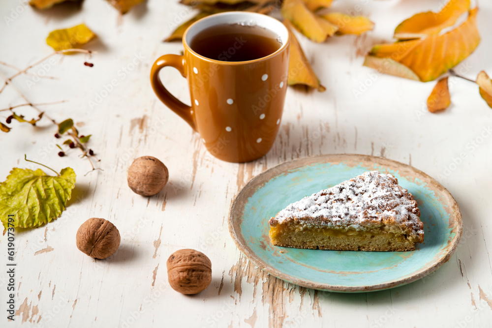 Baked pie served with tea on table with dried leaves and walnuts. autumn composition