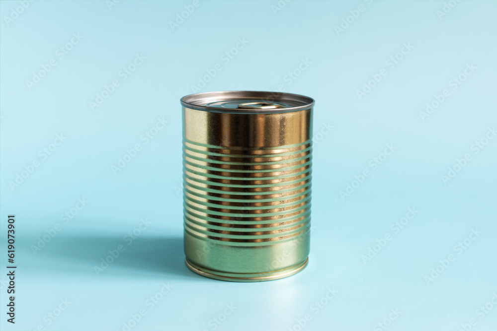 A tin can of golden color in close-up on a blue background. Long-term storage products.