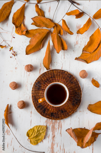 Hot tea on table with dried leaves and walnuts , autumn composition