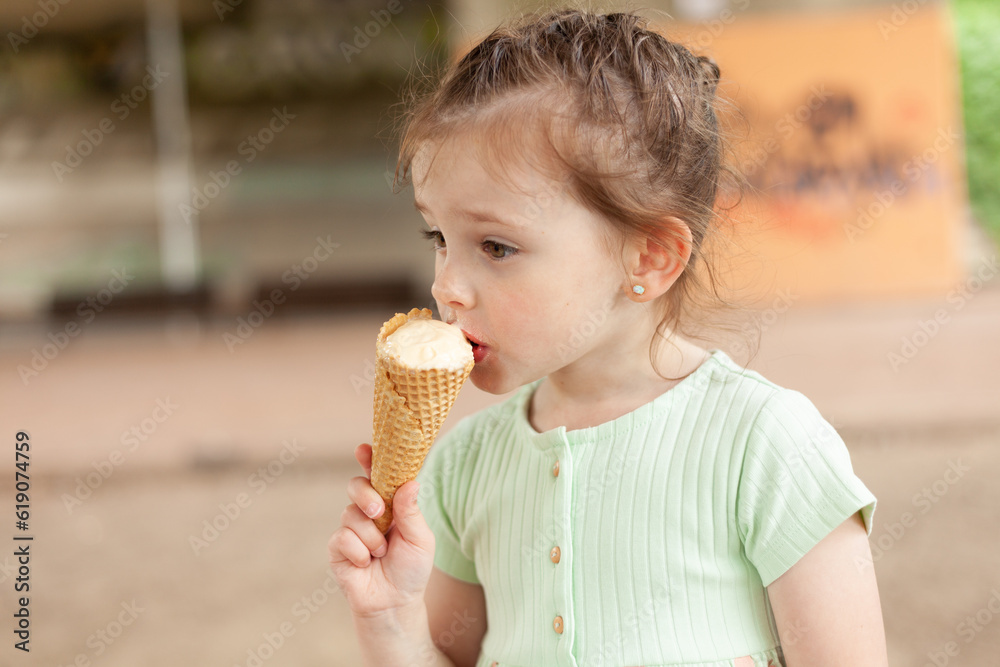 Funny blonde girl in a dress eats an ice cream cone outdoors Funny blonde girl in a dress eats an ice cream cone outdoors