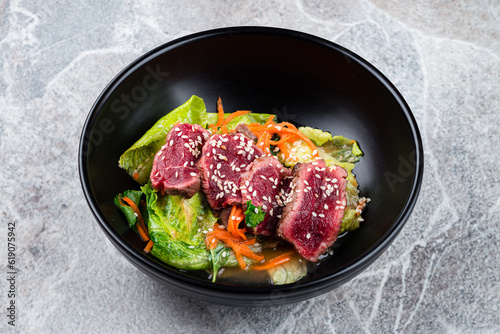 Meat salad with beef, lettuce, carrot, chili, lime, onion, basil and sesame seeds.