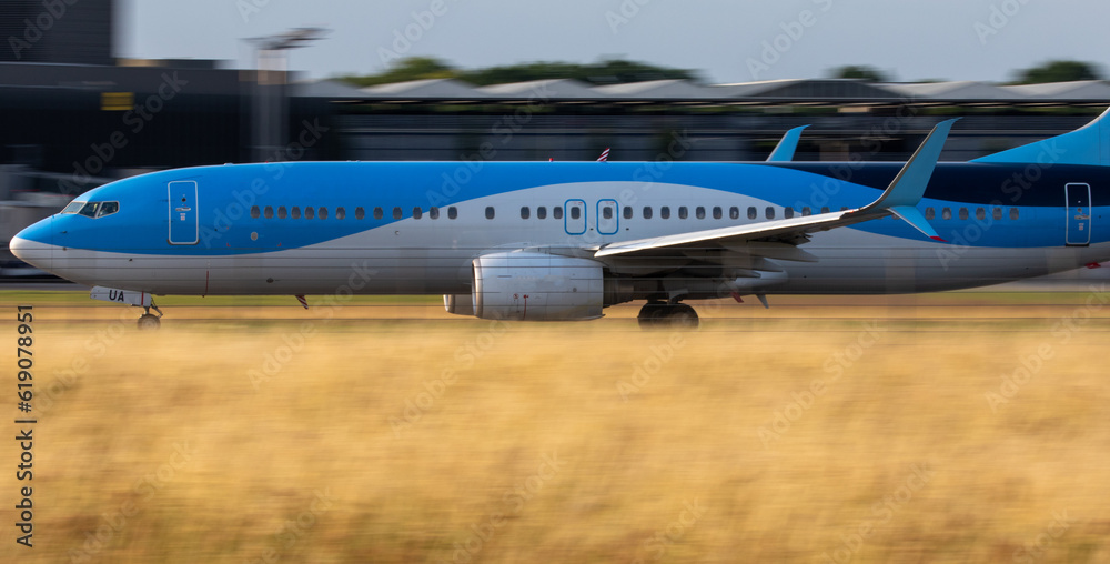 blue and white new passenger airplane taking off from runway without logo with copy space, panning shot blue and white new passenger airplane taking off from runway without logo with copy space, panning shot